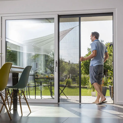 Moustiquaire coulissante sur baie vitrée donnant sur jardin
